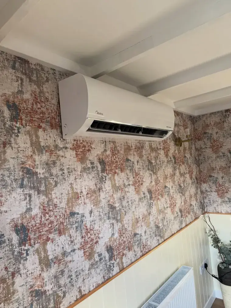 Air conditioning unit fitted on a papered wall above a radiator
