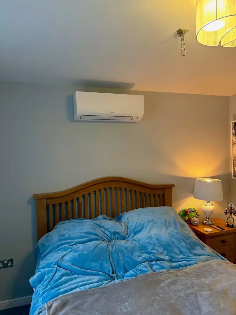 Air conditioning unit on a bedroom wall beside a lamp