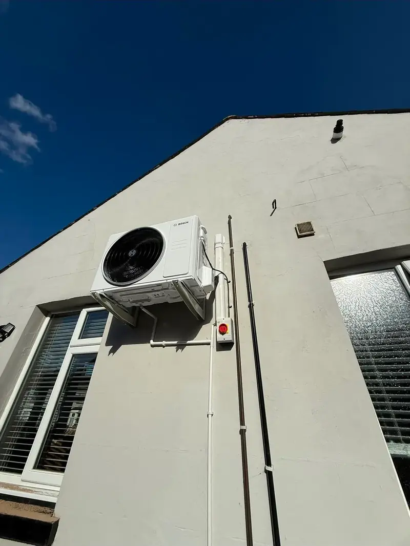 Air conditioning condenser bracketed high on a rendered external wall