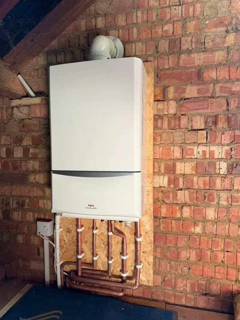 Boiler fitted to an exposed brick wall with copper pipework run below it