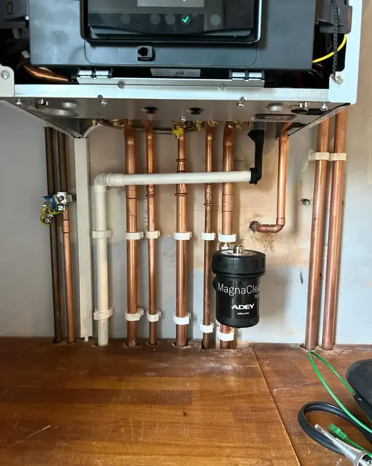Copper pipework and a magnetic filter run neatly beneath a boiler