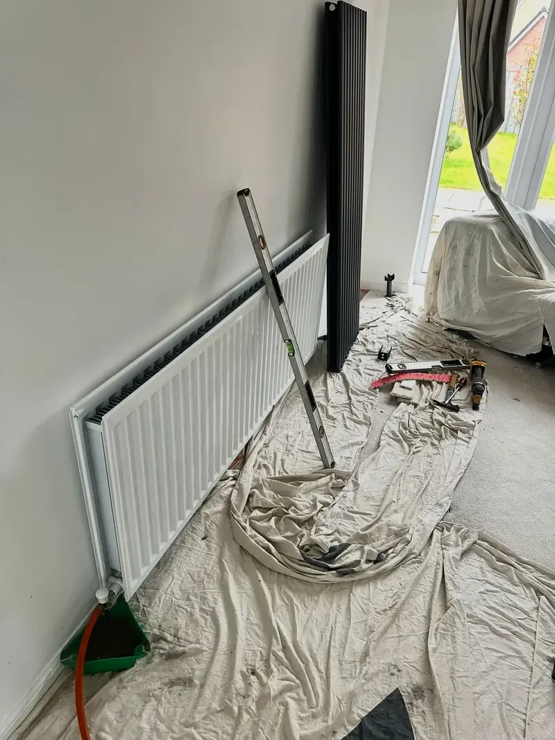 A new panel radiator going on the wall, dust sheets down across the carpet