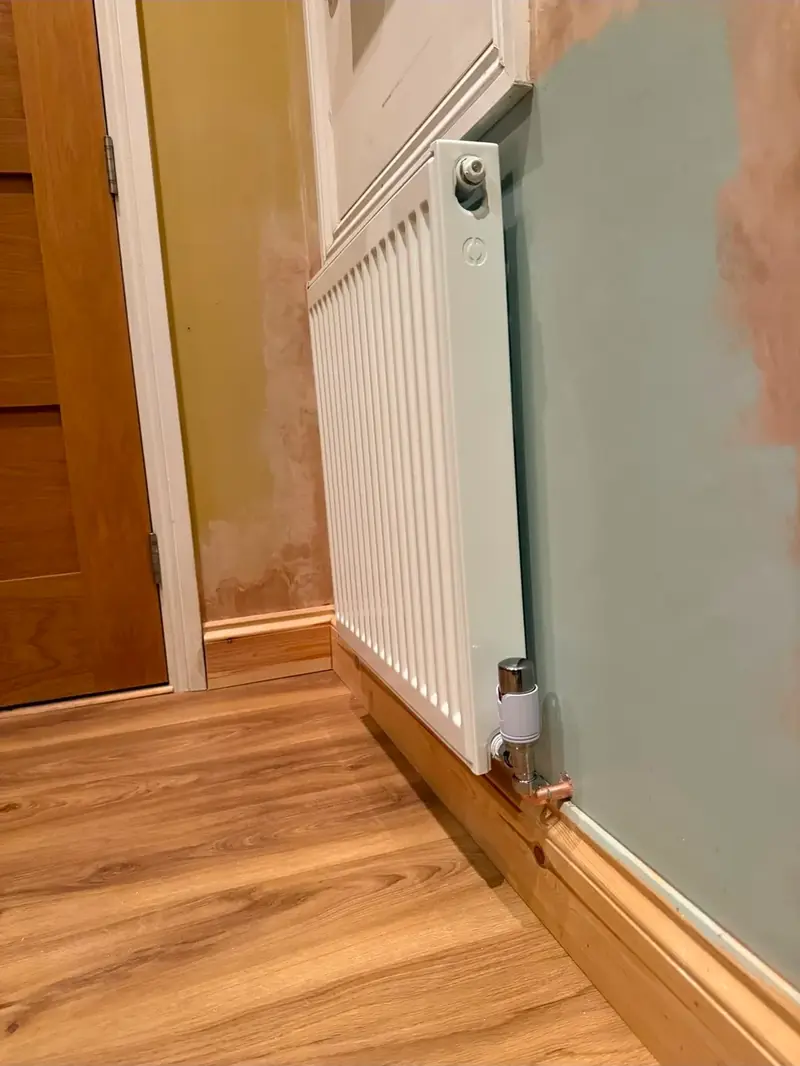 Panel radiator fitted to a painted wall with a thermostatic valve
