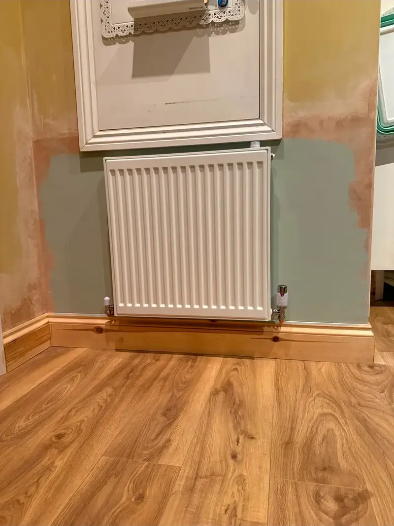 Panel radiator fitted in a hallway above a wood floor
