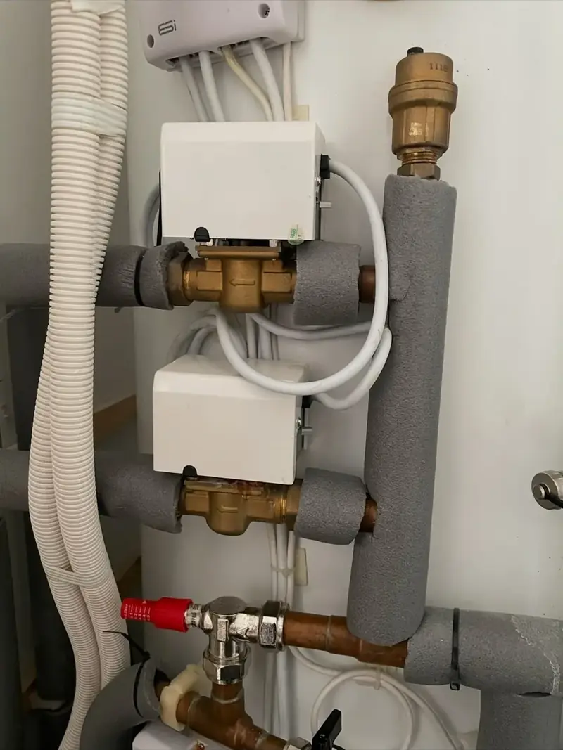 Two motorised zone valves and an automatic air vent on insulated pipework