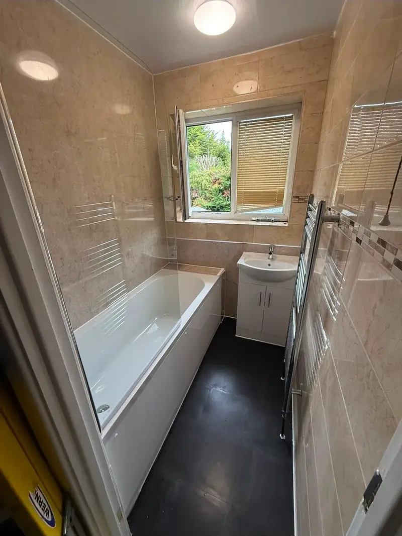 Finished bathroom with a panelled bath, vanity unit and heated towel rail