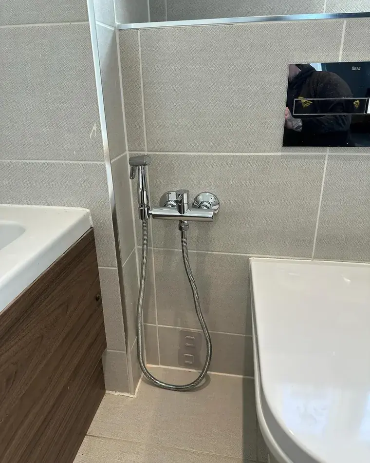 Finished bathroom with a bath, shower fittings and tiled walls