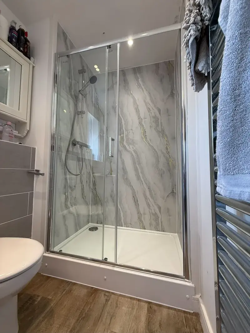 Finished corner shower enclosure with marble-effect wall panels